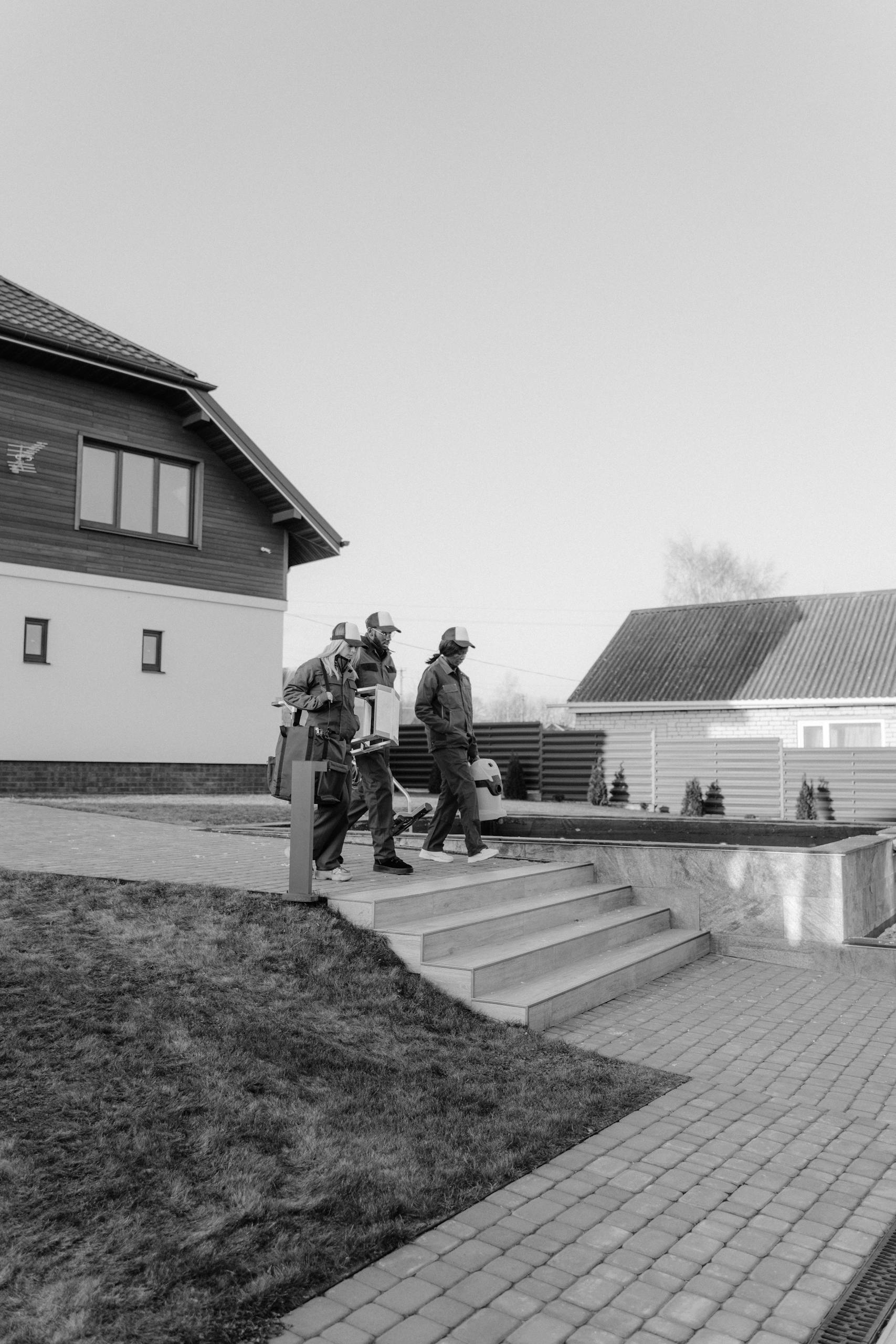 Workers in uniform walking outside a modern home in a residential area.