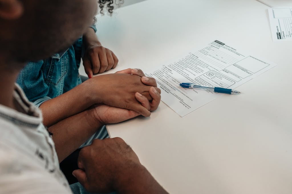 A family supports each other during an adoption process, holding hands over important documents.