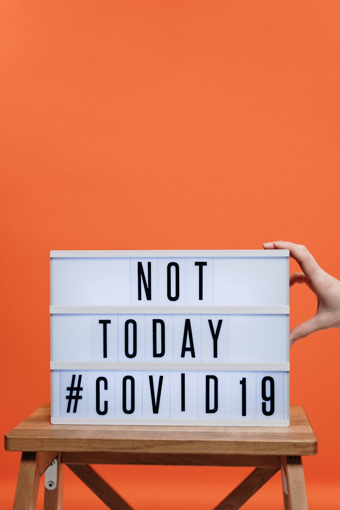 A motivational sign reading 'NOT TODAY #COVID19' against a bright orange background, symbolizing resilience.